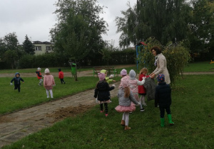 Dzieci zbierają śmieci w ogrodzie przedszkolnym.